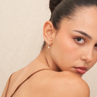 Close-up of a woman wearing a delicate earring against a neutral background