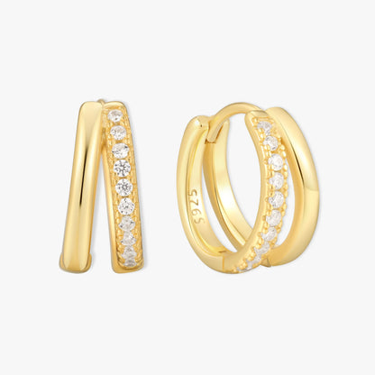 Gold double hoop earrings with embedded diamonds on a light gray background