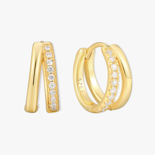 Gold double hoop earrings with embedded diamonds on a light gray background