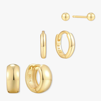 Set of gold earrings including hoop, ball, and small hoop on a white background