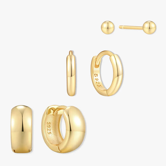 Set of gold earrings including hoop, ball, and small hoop on a white background